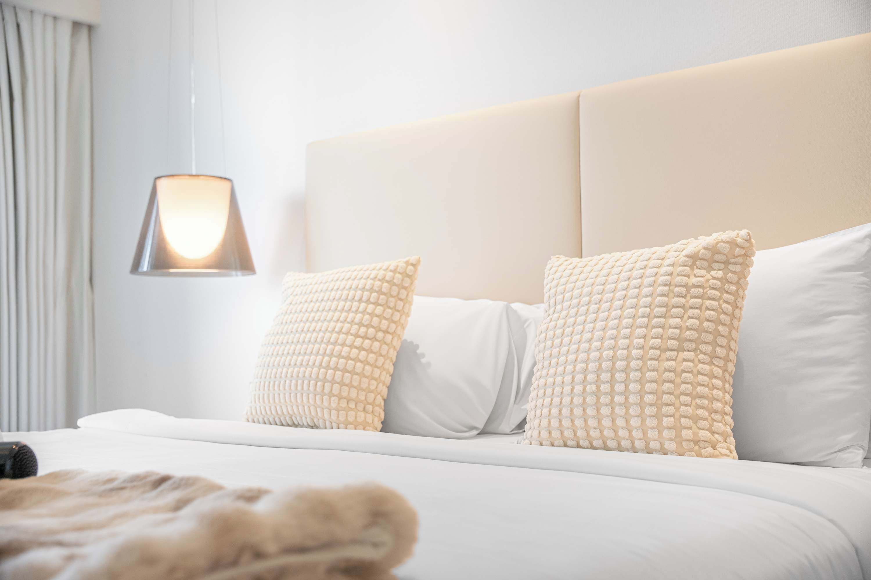 Une chambre d’hôtel avec un lit, des oreillers, une lampe et une couverture.