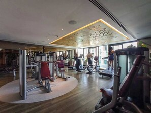 Ein modernes Fitnessstudio mit unterschiedlichen Trainingsgeräten, großen Fenstern und Holzboden.