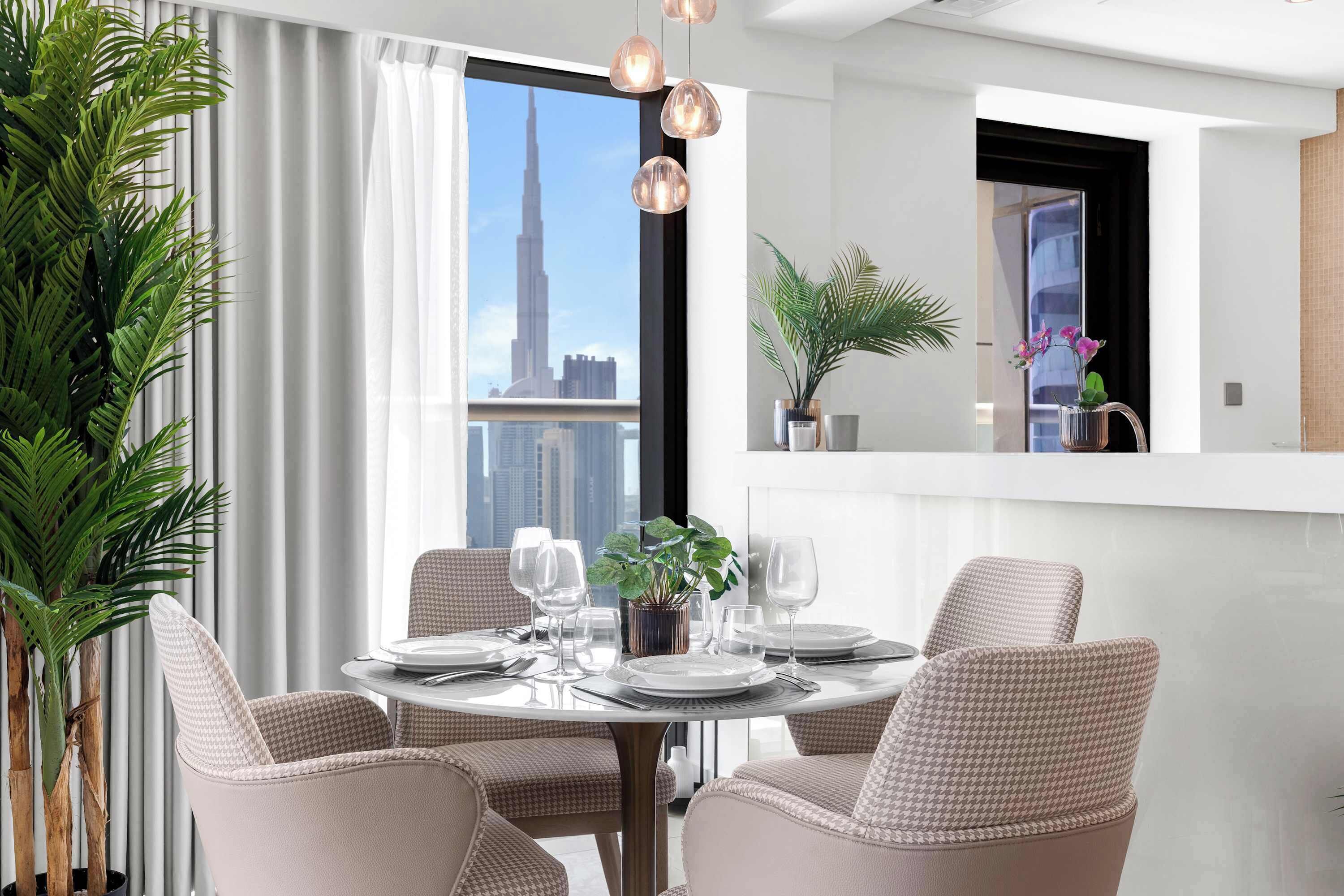 A dining area with a round table, four chairs, and a view of a tall building.