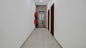 Ein Flur mit an der Wand montiertem Feuerlöscher, einer Tür am Ende und einem gefliesten Boden.