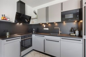 A modern kitchen with a built-in oven, a microwave, and a sink.