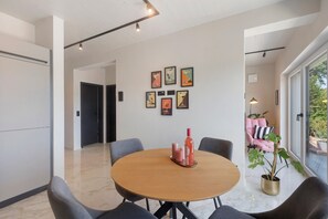 A modern dining area with a round table, grey chairs, and a potted plant.