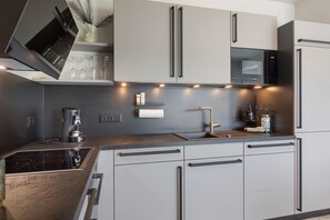 A modern kitchen with a built-in stove, a microwave, and a sink.