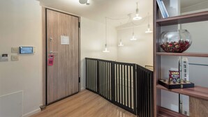 Un couloir avec une porte en bois, une pancarte « Ne pas déranger », un radiateur et une bibliothèque sur laquelle se trouve un bol rempli de pommes de pin.