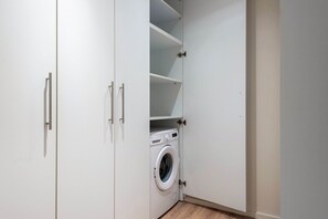Une buanderie équipée d’un lave-linge, de placards et d’étagères.