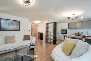 Ein modernes Wohnzimmer mit einem Glastisch, einem weißen Sofa und einem Gemälde an der Wand.
