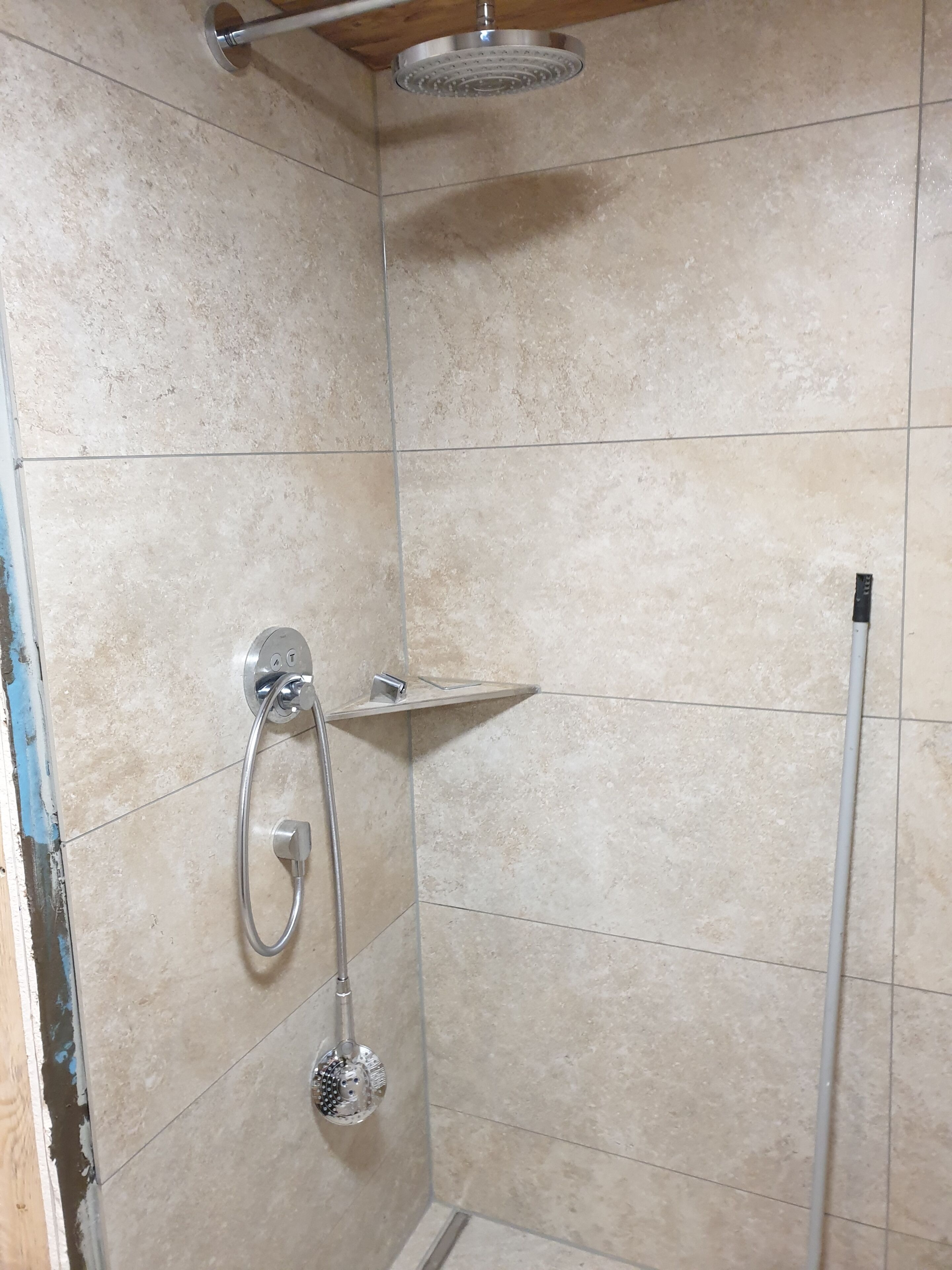 Eine Dusche mit Handbrause und am Wand befestigtem Wasserhahn.