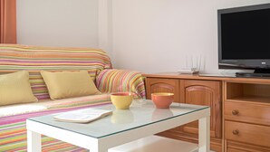 Ein ordentlich eingerichtetes Schlafzimmer mit einem Bett, einem Schreibtisch mit Computer und einem Fernseher.