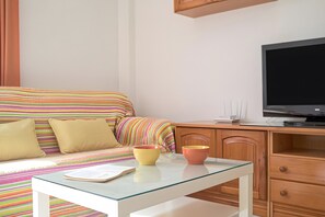 Ein ordentlich eingerichtetes Schlafzimmer mit einem Bett, einem Schreibtisch mit Computer und einem Fernseher.