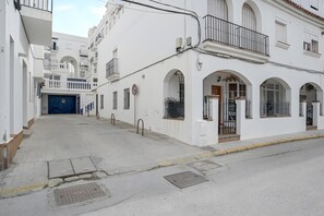 A narrow street with white buildings, a blue gate, and a metal gate. - Tomy Apartment – Families Only, Sea View, Balcony, Wi-Fi (Conil de la Frontera)
