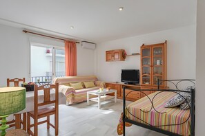 A compact living space with a sofa, a dining table, a TV, and a cabinet. - Tomy Apartment – Families Only, Sea View, Balcony, Wi-Fi (Conil de la Frontera)
