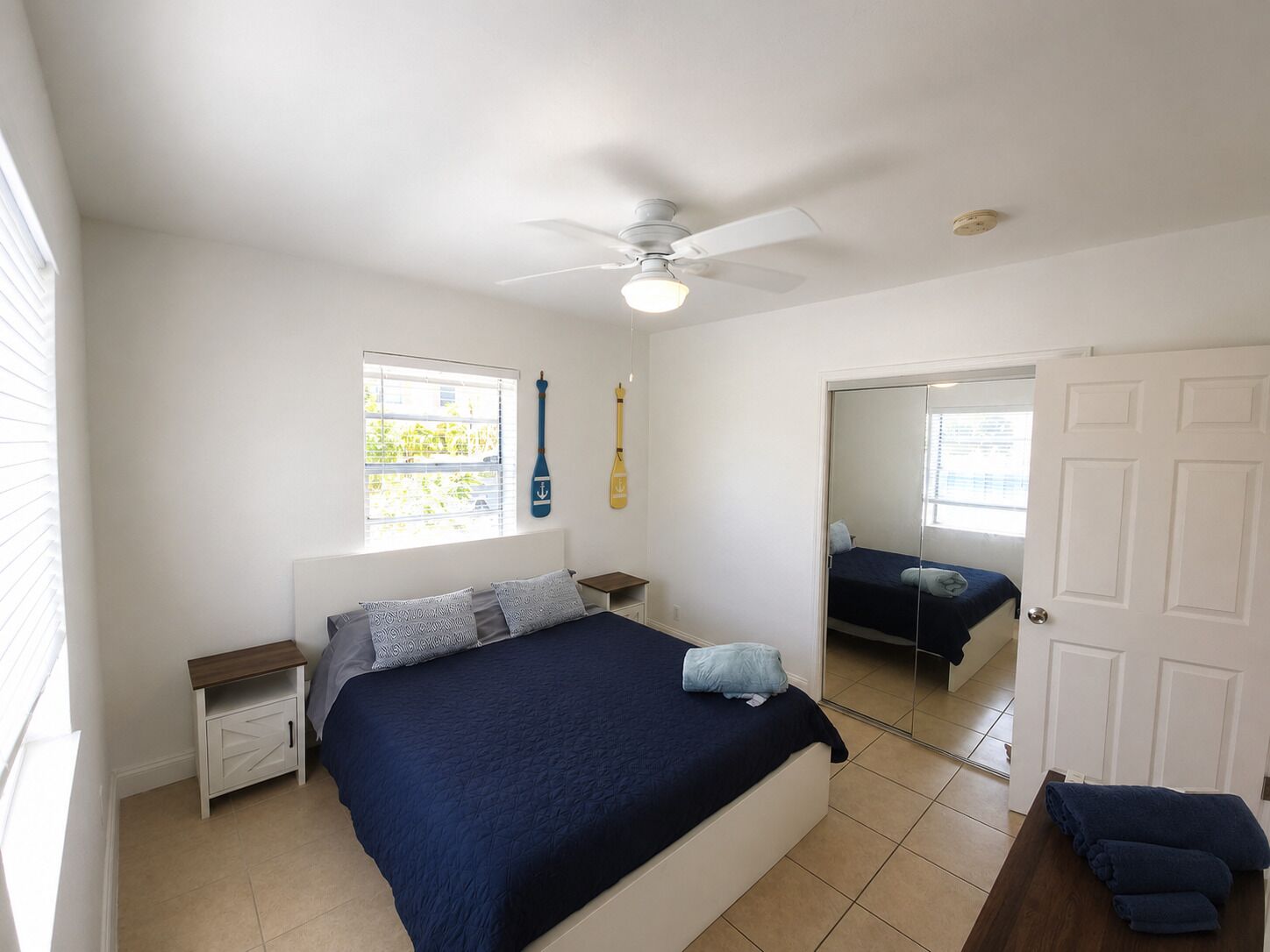 A bedroom with a bed, a ceiling fan, a window, and a door.