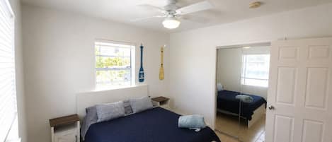 Un dormitorio con cama, ventilador de techo, ventana y puerta.