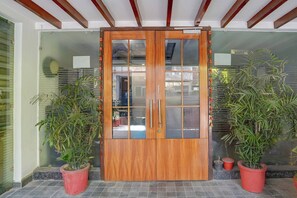 A wooden double door with glass panels, flanked by potted plants. - Super Townhouse by Zirakpur Bus Stand (Zirakpur)