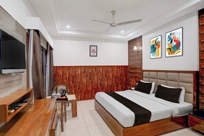 A modern hotel room with a bed, a desk, a television, and artwork on the walls. - Super Townhouse by Zirakpur Bus Stand (Zirakpur)