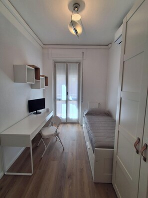 A bedroom with a bed, a desk with a computer, a chair, a wardrobe, and a sliding glass door. - MILARIO 162 - Central and stylish apartment with AC and a balcony (Como)
