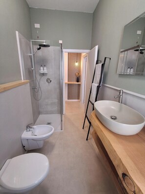 Ein modernes Badezimmer mit Dusche, zwei Waschbecken und Toilette.