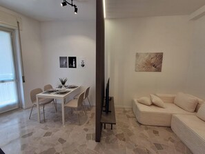 A dining area with a table set for four, a sofa, and a painting on the wall. - MILARIO 162 - Central and stylish apartment with AC and a balcony (Como)