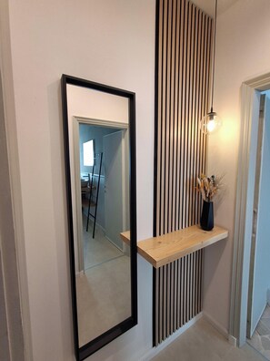 A hallway with a mirror, a wooden shelf, and a wall with vertical slats. - MILARIO 162 - Central and stylish apartment with AC and a balcony (Como)