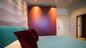 Ein modernes Schlafzimmer mit einem großen Bett, einer Kopfteil, einem Kleiderschrank und einer Tür.