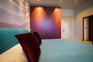 Ein modernes Schlafzimmer mit einem großen Bett, einer Kopfteil, einem Kleiderschrank und einer Tür.