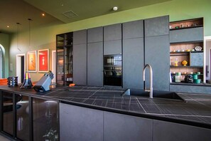 A modern kitchen with a central island, built-in appliances, and a coffee station. - Luxury Countryside Retreat with Pool, Spa & Gym (Zebbug)