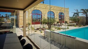 Ein modernes Gebäude mit großen Bogenfenstern, einem Pool und Sitzgelegenheiten im Freien.