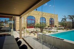 Ein modernes Gebäude mit großen Bogenfenstern, einem Pool und Sitzgelegenheiten im Freien.