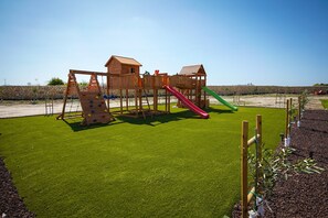 A playground with a climbing wall, slides, and a wooden playhouse. - Luxury Countryside Retreat with Pool, Spa & Gym (Zebbug)