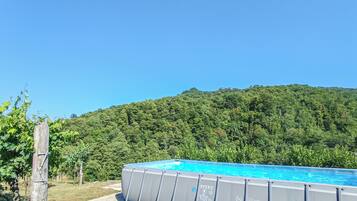 An outdoor swimming pool with a view of a forested hill.