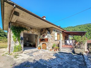 A stone building with a stone roof, a wooden door, and a small garden area with potted plants. - Il Rifugio di Anna (Tresana)