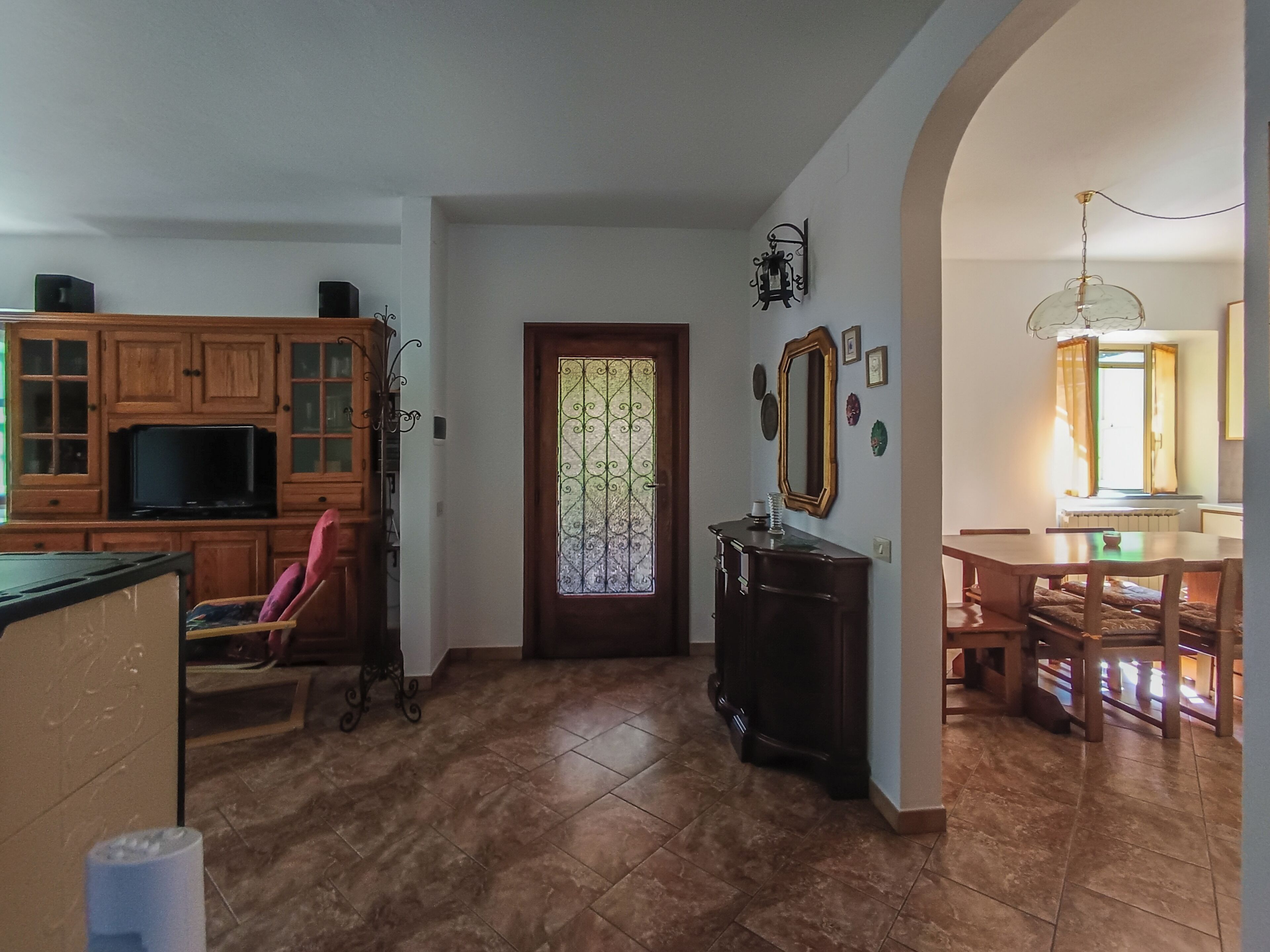 A kitchen with wooden cabinets, a television, and a dining area with a table and chairs.