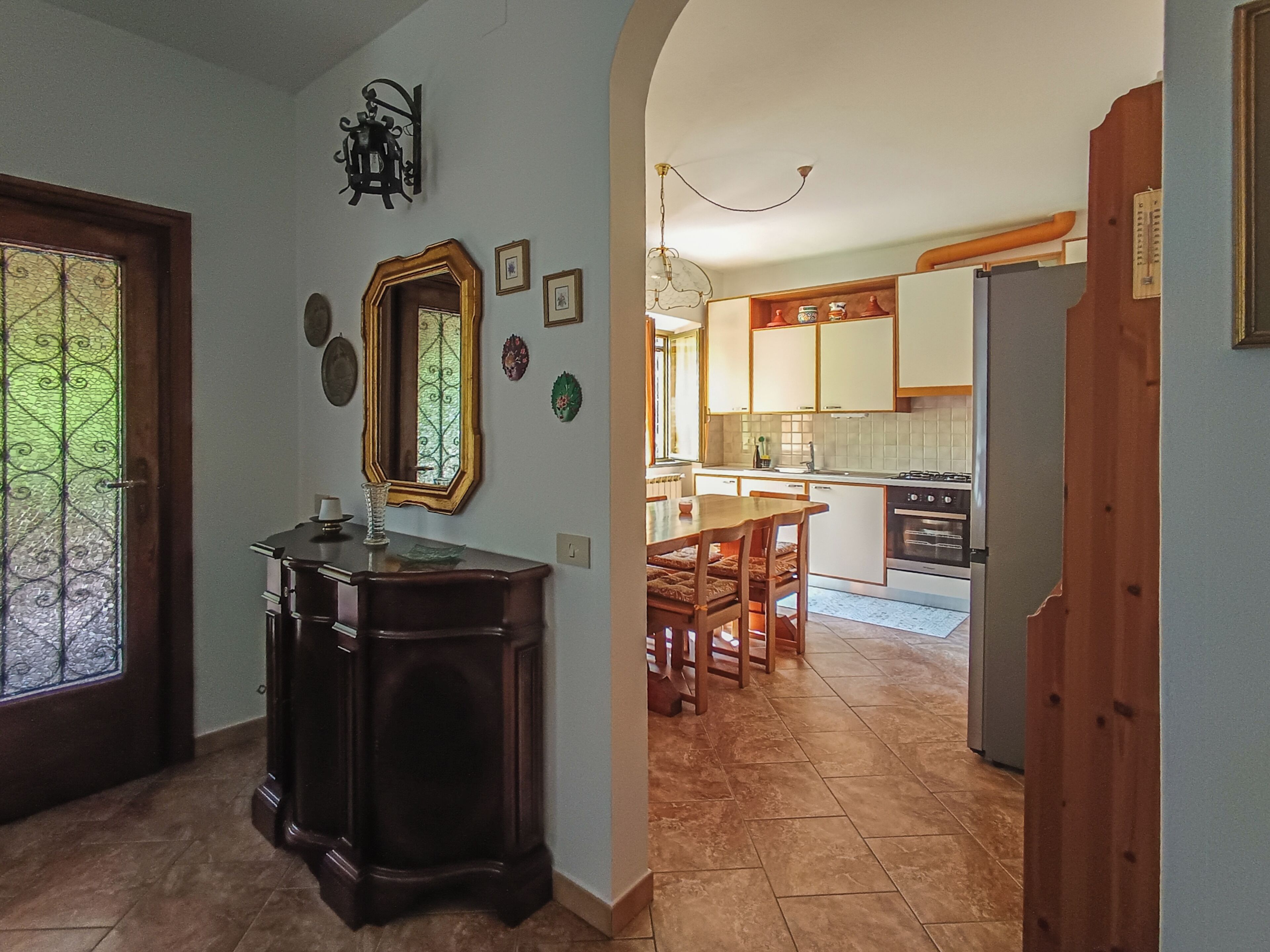 A kitchen with wooden cabinets, a dining table, and a chandelier.
