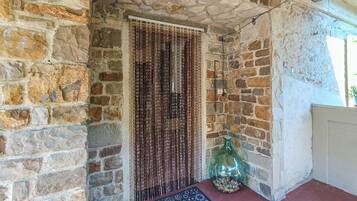 A stone-walled room with a patterned rug, a decorative bottle, and a hanging light fixture.
