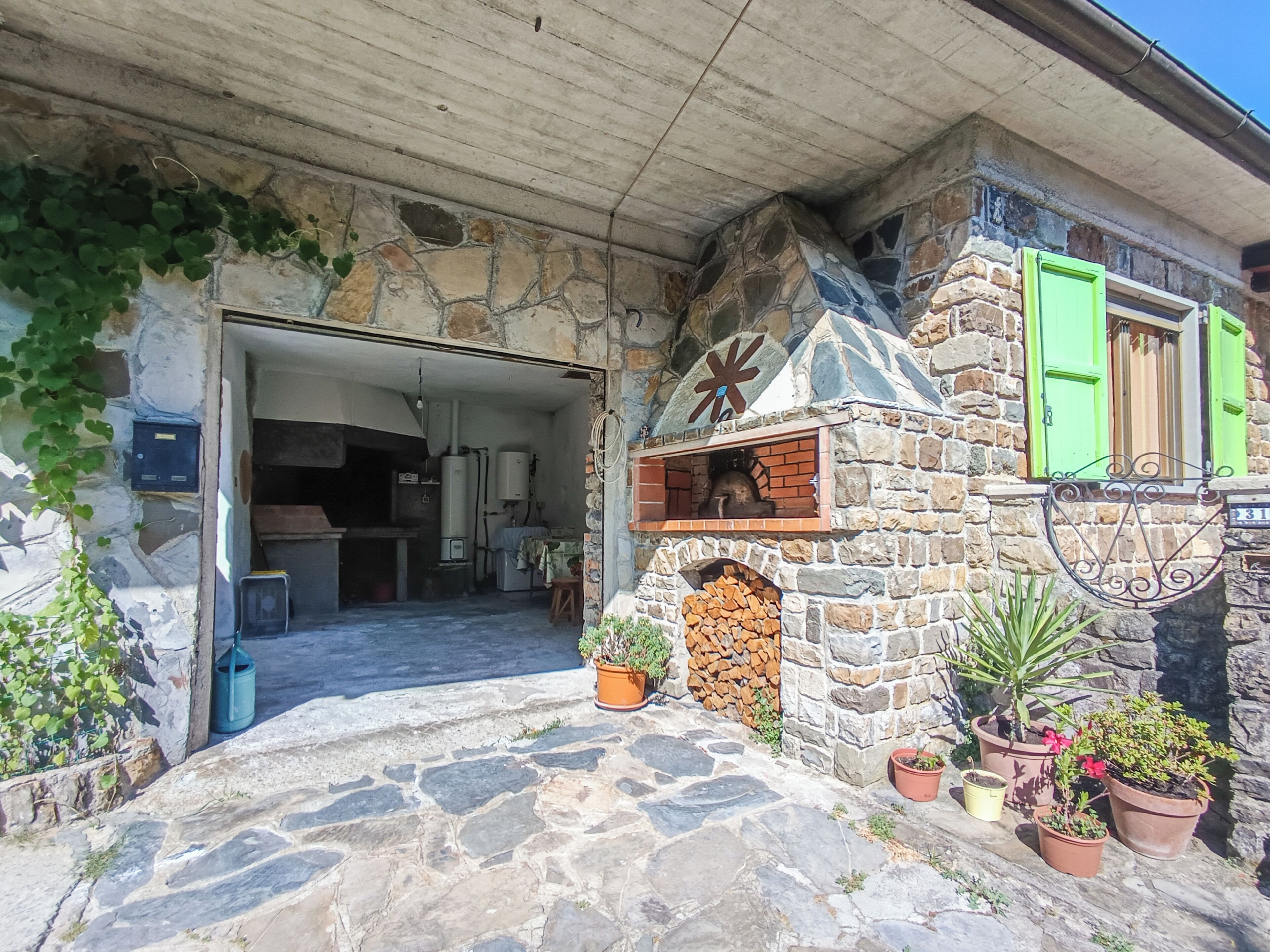 A stone building with a fireplace, potted plants, and a wooden door.