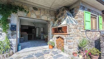A stone building with a fireplace, potted plants, and a wooden door.