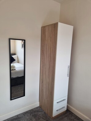 Une chambre avec une armoire, un miroir et un lit.