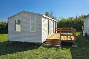 A small, single-story mobile home with a wooden deck and a ramp leading to the entrance. - Violettes - two-bedroom Parc Home combines comfort, practicality, and charm. (Lévignac-de-Guyenne)