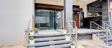 A hotel entrance with marble steps, a glass door, and potted plants.