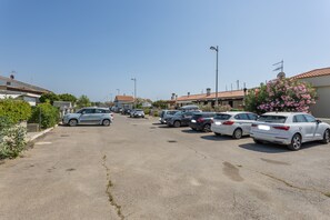 A parking lot with multiple cars, buildings with red-tiled roofs, and a clear sky. - Holiday Home 'Sul Porto – Steps from the Sea' with Sea View, Private Terrace & AC (Grosseto)
