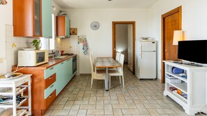 Eine kompakte Küche mit Essbereich, Deckenventilator, Kühlschrank und Fernseher auf einem Schrank.