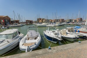 A marina with multiple boats docked, a building with a flag, and a clear sky. - Holiday Home 'Sul Porto – Steps from the Sea' with Sea View, Private Terrace & AC (Grosseto)