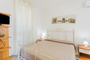 Een slaapkamer met een bed, nachtkastjes, een televisie en een wandplank met planten.