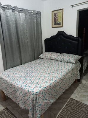 A bedroom with a bed, grey curtains, a framed picture on the wall, and a door to the right. - THE PLAYMAKER GIRLS  NEXT GALAXY VILLA MBJ (Montego Bay)