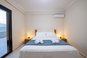 A hotel room with a bed, two bedside lamps, a window, and an air conditioning unit.