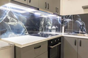 Una cocina con encimera negra, horno empotrado y salpicadero con estampado de rayos.