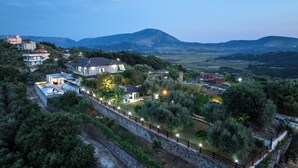 A residential area with multiple houses, a swimming pool, and a stone retaining wall. - Villa Verde (Aliko)