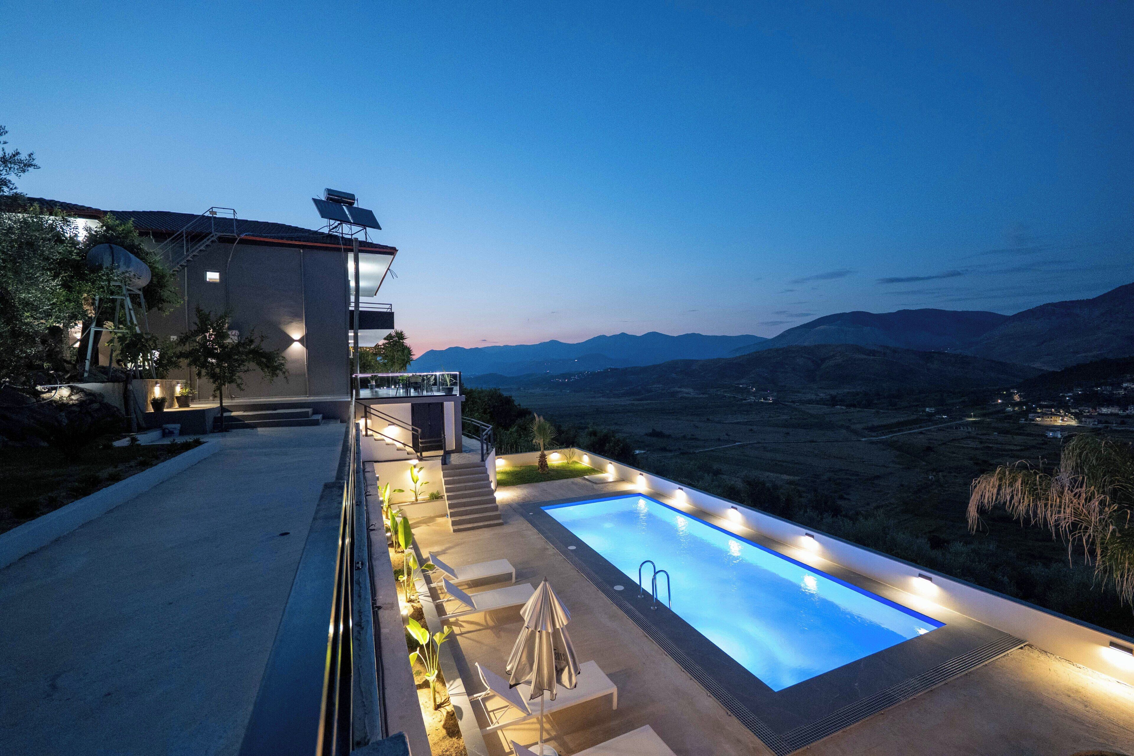 Une maison moderne dotée d’une piscine, d’un espace salon extérieur et offrant une vue sur les montagnes.