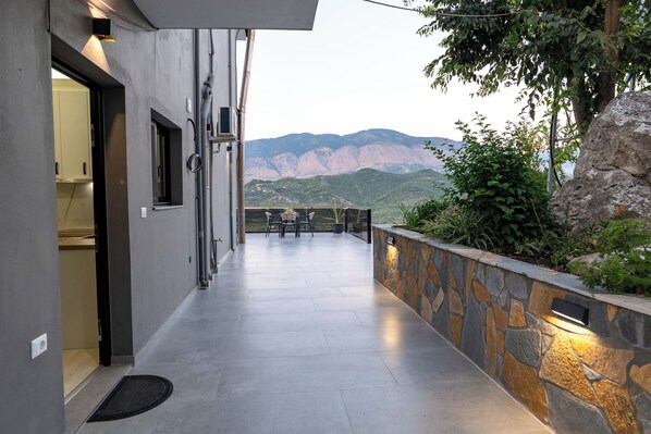 A corridor with a view of mountains, a stone wall, and a door leading to a room. - Villa Verde (Aliko)