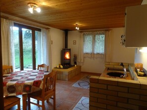 Ein gemütliches Zimmer mit Kamin, einem Esstisch und einer Küchenzeile.